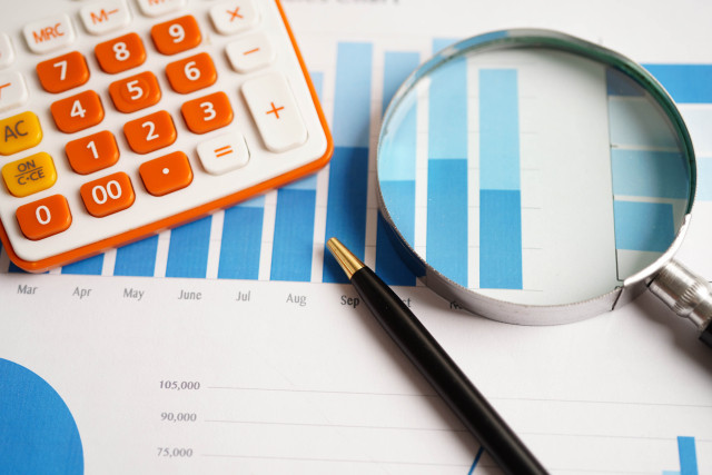 bar graphs on paper with a calculator and magnifying glass