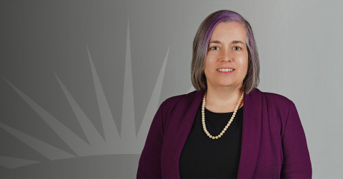 Headshot of Laura Maxwell with sunburst in background
